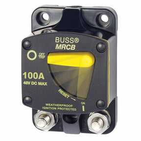 A black surface mount circuit breaker with a yellow reset button, labeled '100A 48V DC MAX' and 'MRCB', with recessed mounting holes.